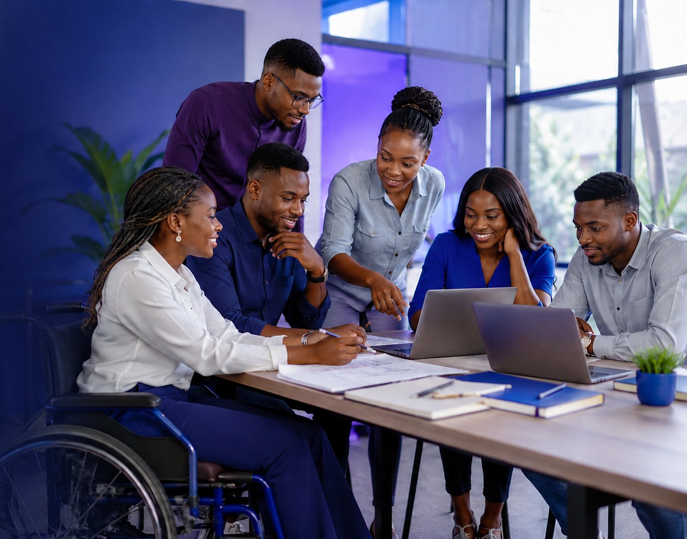 A team of young African professionals, including a wheelchair user, collaborating around laptops